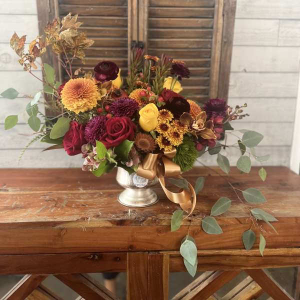 Mixed bouquet in a silver vase with red, yellow, and orange flowers