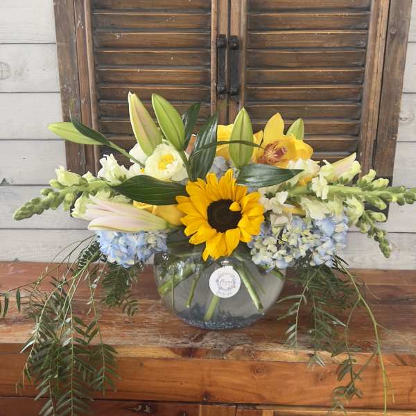 Yellow sunflower and lilies arranged in a glass bowl vase