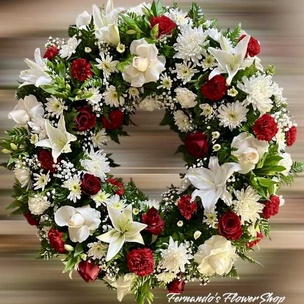 Circular wreath with white lilies, red roses, white mums, and red carnations