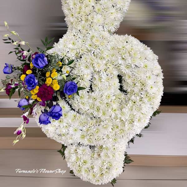 Standing white chrysanthemum ribbon arrangement with blue roses and mixed accent flowers.