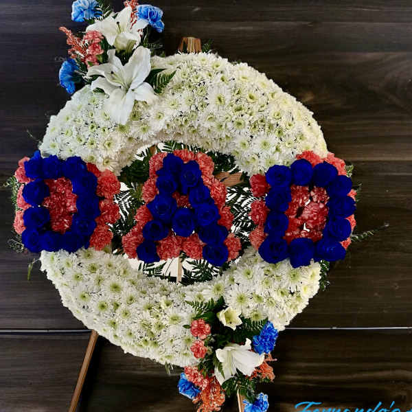 Standing sympathy wreath with white mums and blue and red flowers spelling DAD on an easel