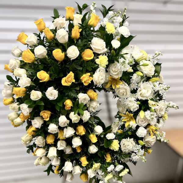Standing open-circle wreath of white and yellow flowers on an easel