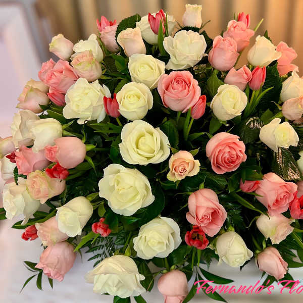 Large dome of white and blush pink roses with small red tulips in a rounded arrangement