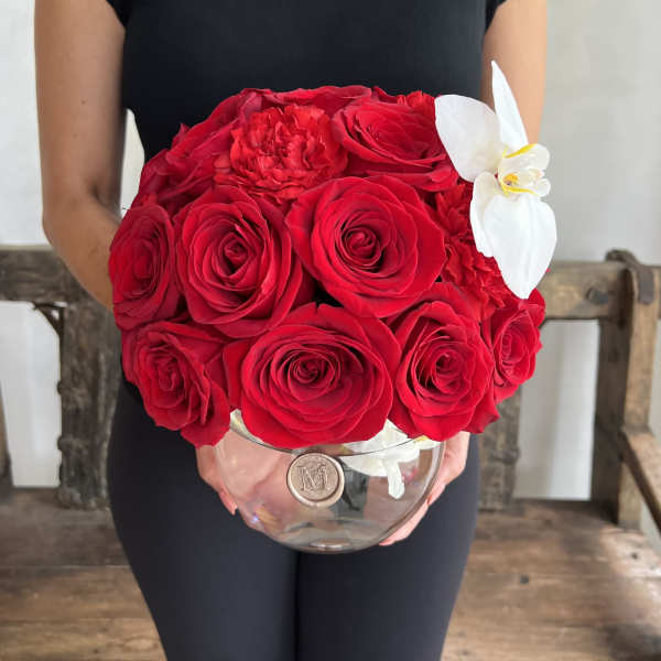 Red rose bouquet with a white orchid in a clear glass vase
