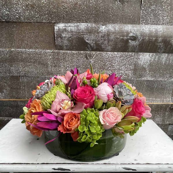 Colorful mixed flower arrangement in a low green glass bowl