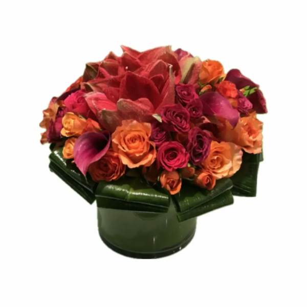 Mixed bouquet of red, orange, and pink flowers in a green vase