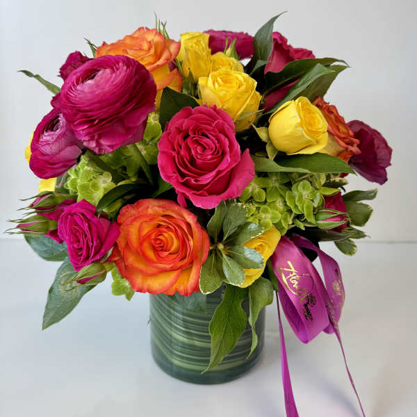 Bright mixed bouquet of roses and ranunculus in a glass vase