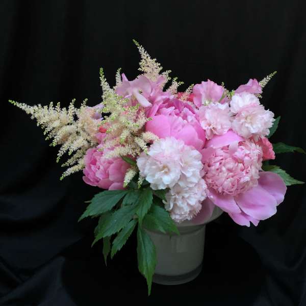 Pink floral arrangement in a white vase with feathery white accents