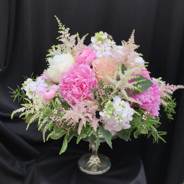 Pink and white floral arrangement in a glass pedestal vase
