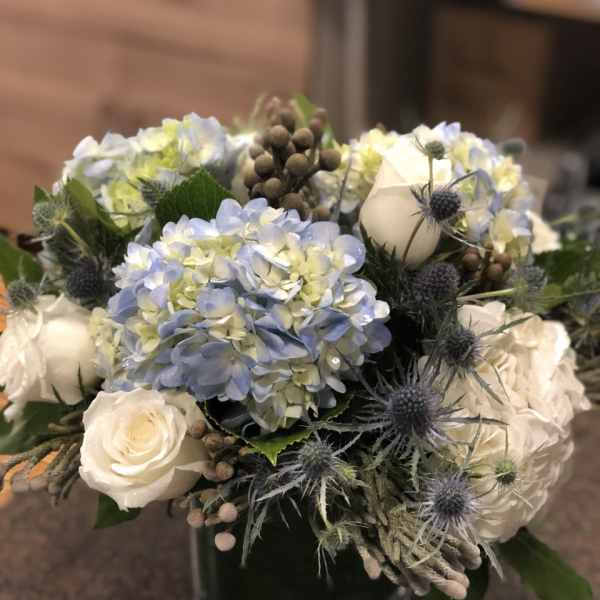 Blue hydrangea and white rose bouquet in a glass vase
