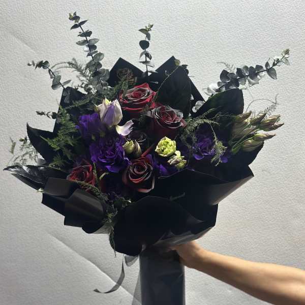 Bouquet of dark red roses and purple lisianthus with black wrapping