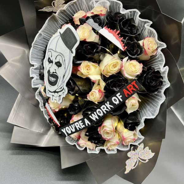 Bouquet of cream and black roses with horror clown decoration and a ribbon reading you’re a work of art.