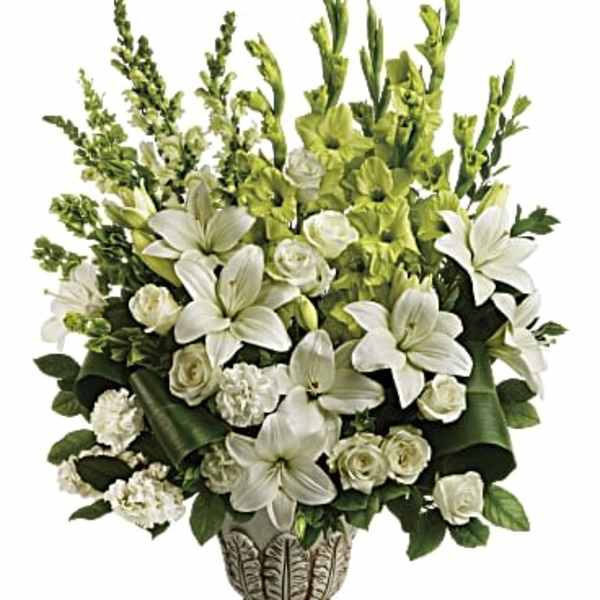 Tall white lily and rose arrangement with green accents in an ornate pedestal vase