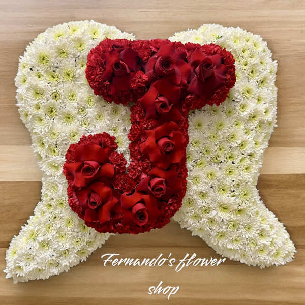 Angel-shaped cushion of white flowers with a red rose letter J on top