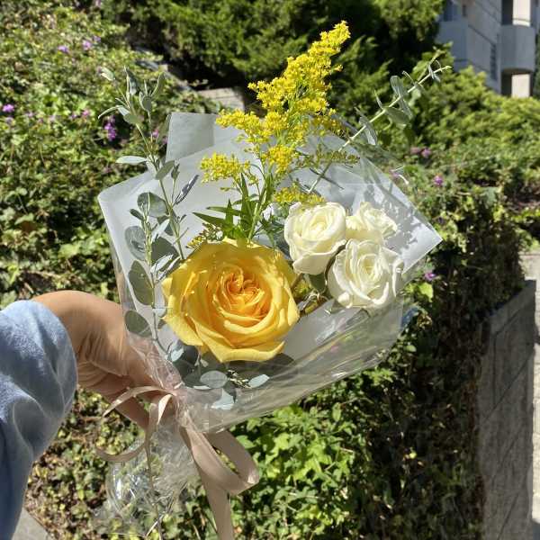 Handheld bouquet of yellow and white roses with airy filler flowers