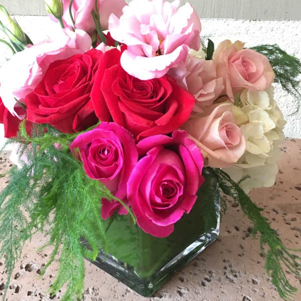 Bouquet of pink and red roses with pale pink blooms in a glass vase
