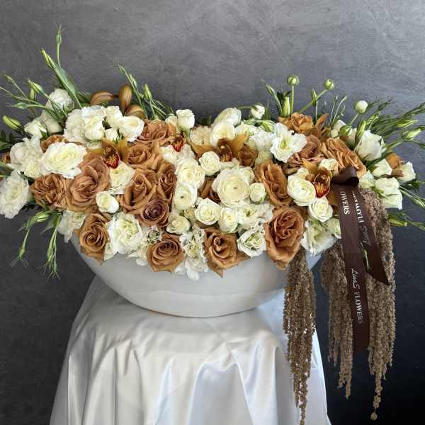 Large floral arrangement of white and caramel roses in a white container