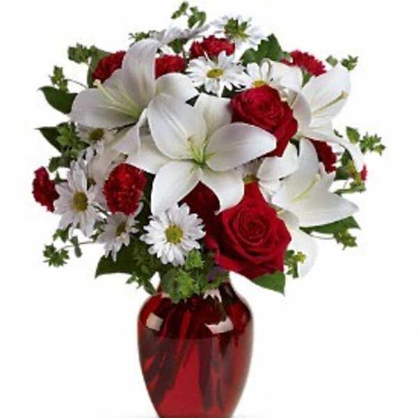 Bouquet of red roses and white lilies in a red glass vase