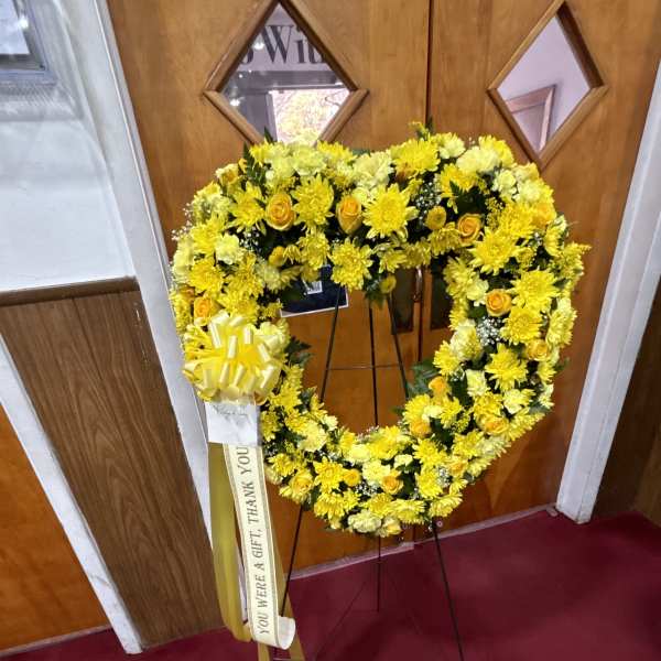 Yellow floral wreath on a stand with a ribbon and bow