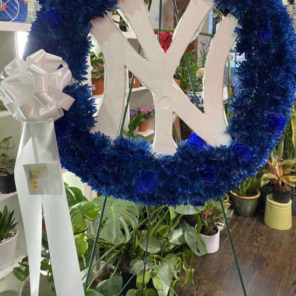Blue floral wreath with a white monogram and ribbon bow on an easel