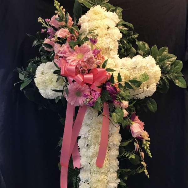 Standing floral cross with pink and white flowers and a pink ribbon