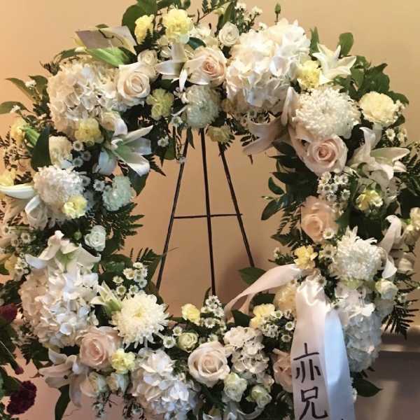 Large white floral wreath with pale pink roses on a stand