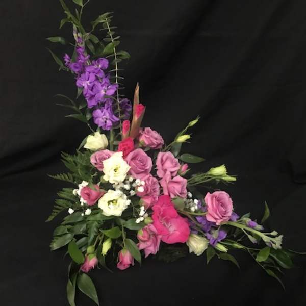 Pink and white floral arrangement with purple flowers on a black background