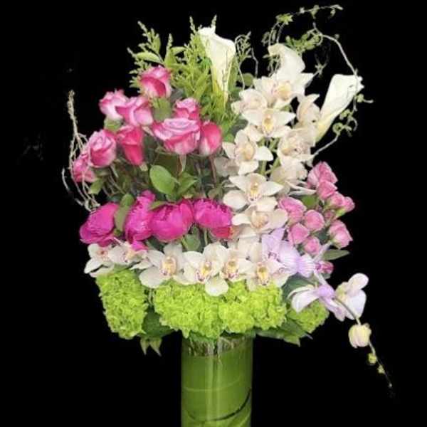 Pink roses and white orchids arranged in a tall glass vase