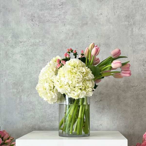 White hydrangeas and pink tulips in a clear glass vase