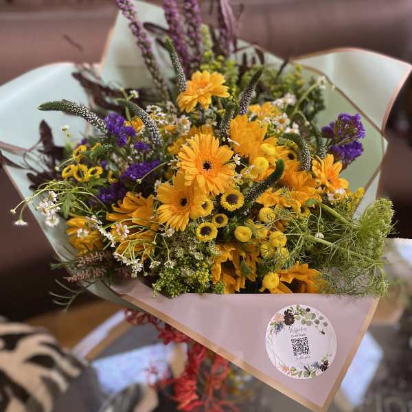 Bouquet of yellow and purple flowers wrapped in pale paper