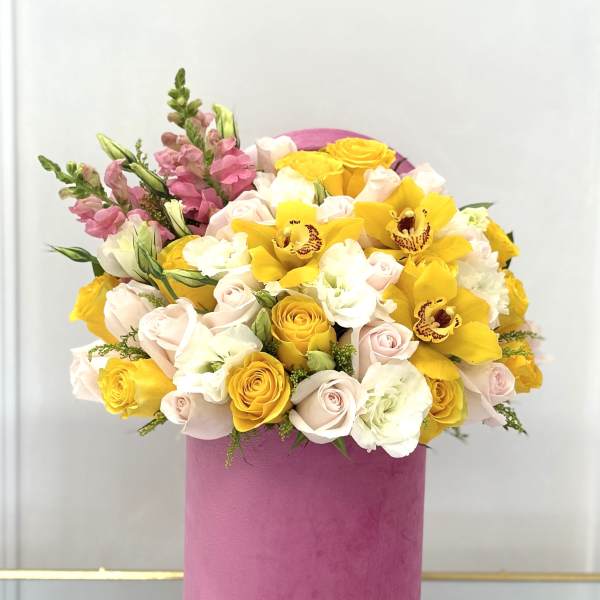 Bouquet of yellow and pale pink roses with yellow orchids in a pink box