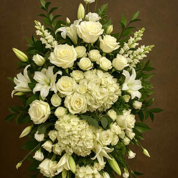 Standing spray of white roses, lilies, and hydrangeas on a wooden easel