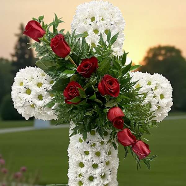 White floral cross with red roses on an outdoor stand