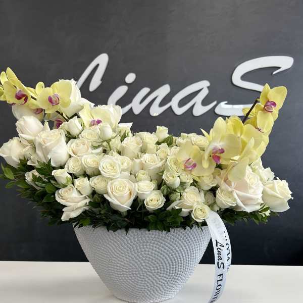 White roses and yellow orchids arranged in a textured white vase
