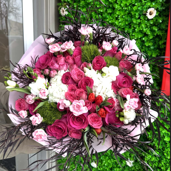 Bouquet of pink and white roses with dark foliage accents