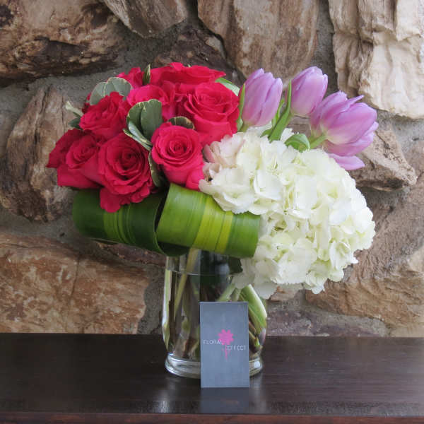 Bouquet of red roses, white hydrangeas, and lavender tulips in a glass vase