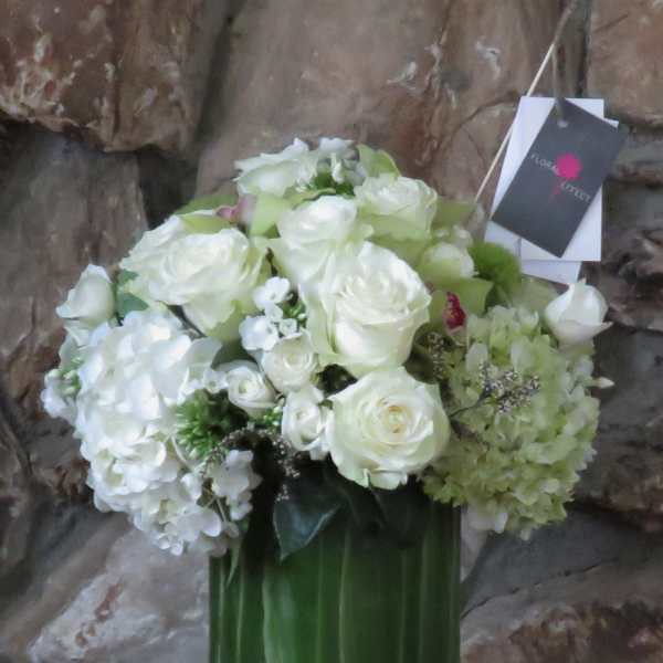 White roses and hydrangeas arranged in a tall green vase
