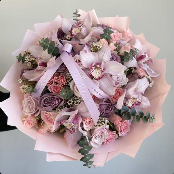 Pink and lavender bouquet with roses and orchids wrapped in pastel paper