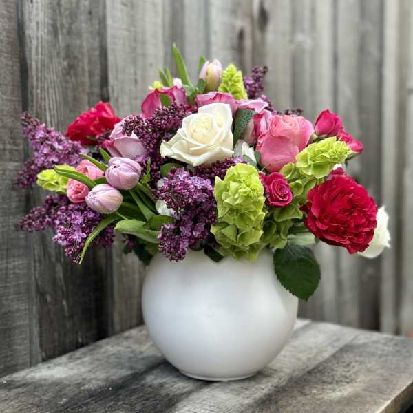 Mixed pink, white, and purple flowers in a white vase