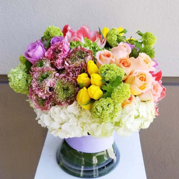 Mixed bouquet of roses, tulips, and hydrangeas in a glass vase