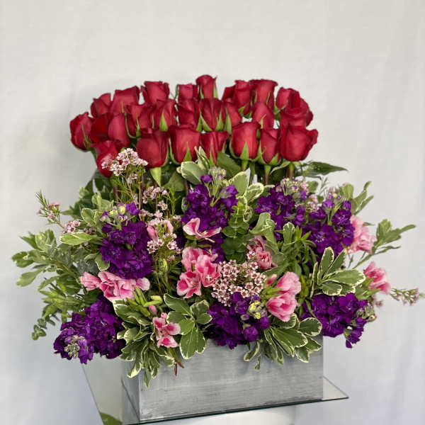 Red roses and purple flowers arranged in a silver box
