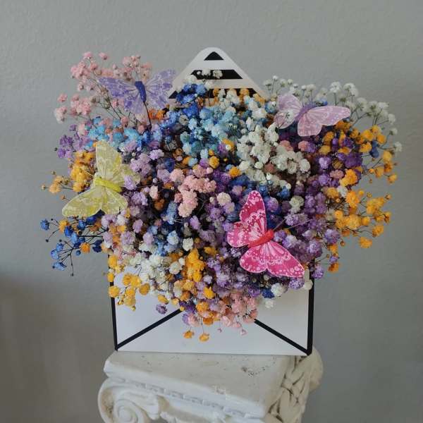 Colorful dried flower bouquet in a white envelope box with butterfly decorations