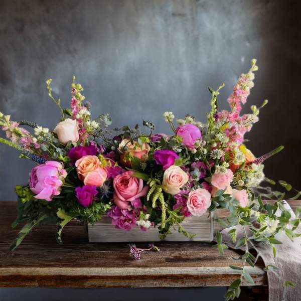 Mixed pink and peach roses in a low rectangular vase arrangement