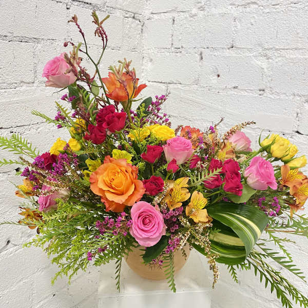 Colorful mixed bouquet of roses and small filler flowers in a round vase