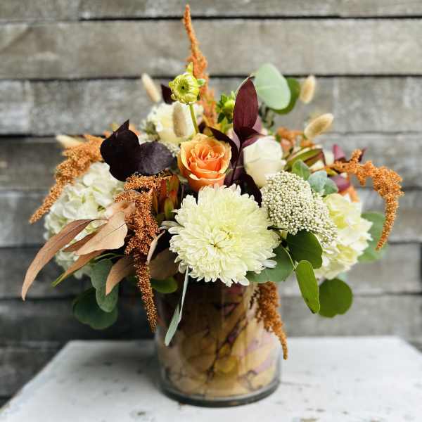 Mixed floral arrangement in a glass vase with orange and white blooms