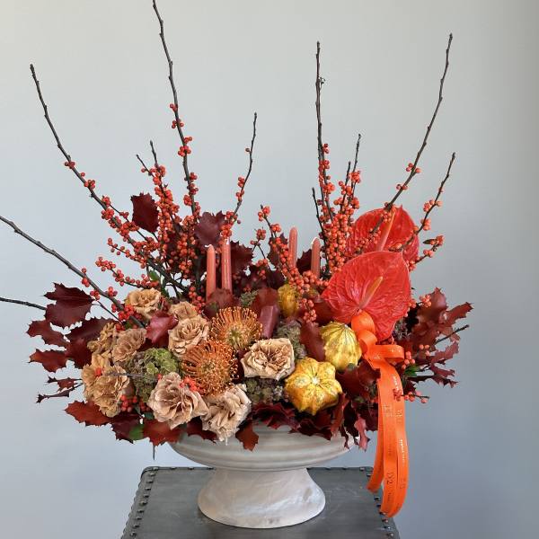 Autumn floral arrangement in a white pedestal vase with orange ribbon