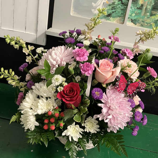 Mixed bouquet of pink, white, and purple flowers in a white container