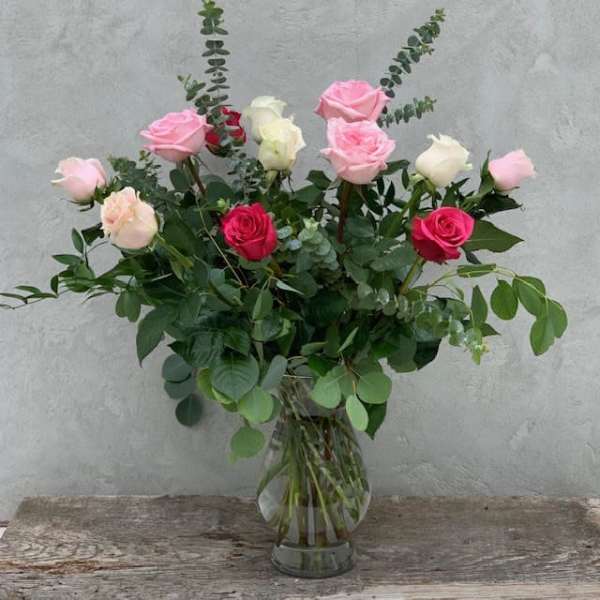 Bouquet of pink, white, and red roses in a clear glass vase