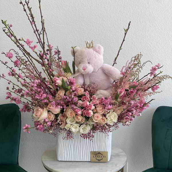 Pink teddy bear in a large arrangement of pink and cream roses