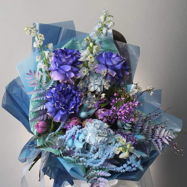 Large bouquet of purple and blue flowers wrapped in blue paper